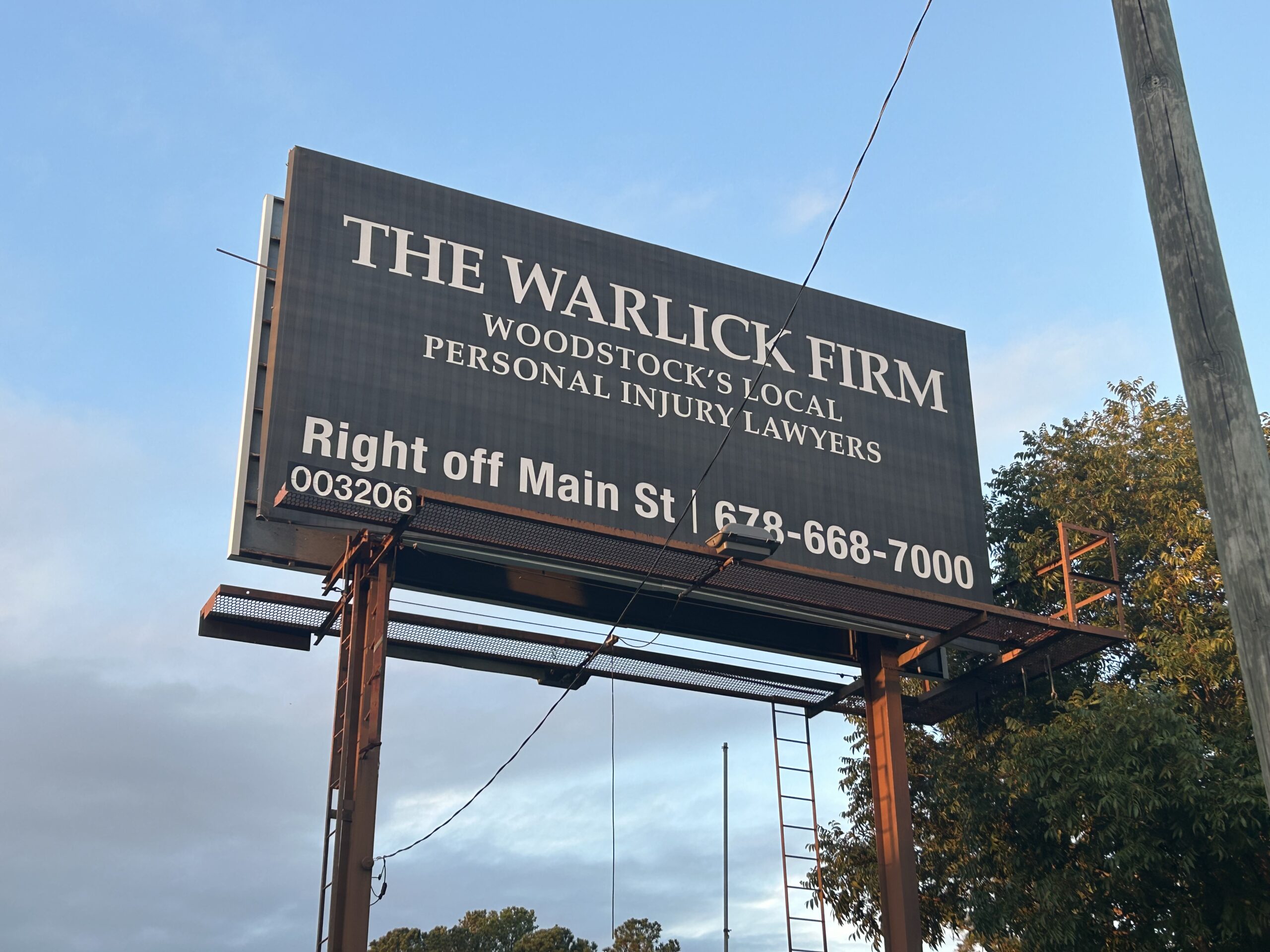 Warlick Firm billboard in Woodstock, Georgia, advertising legal services and guidance on what to do after a shooting in Georgia.