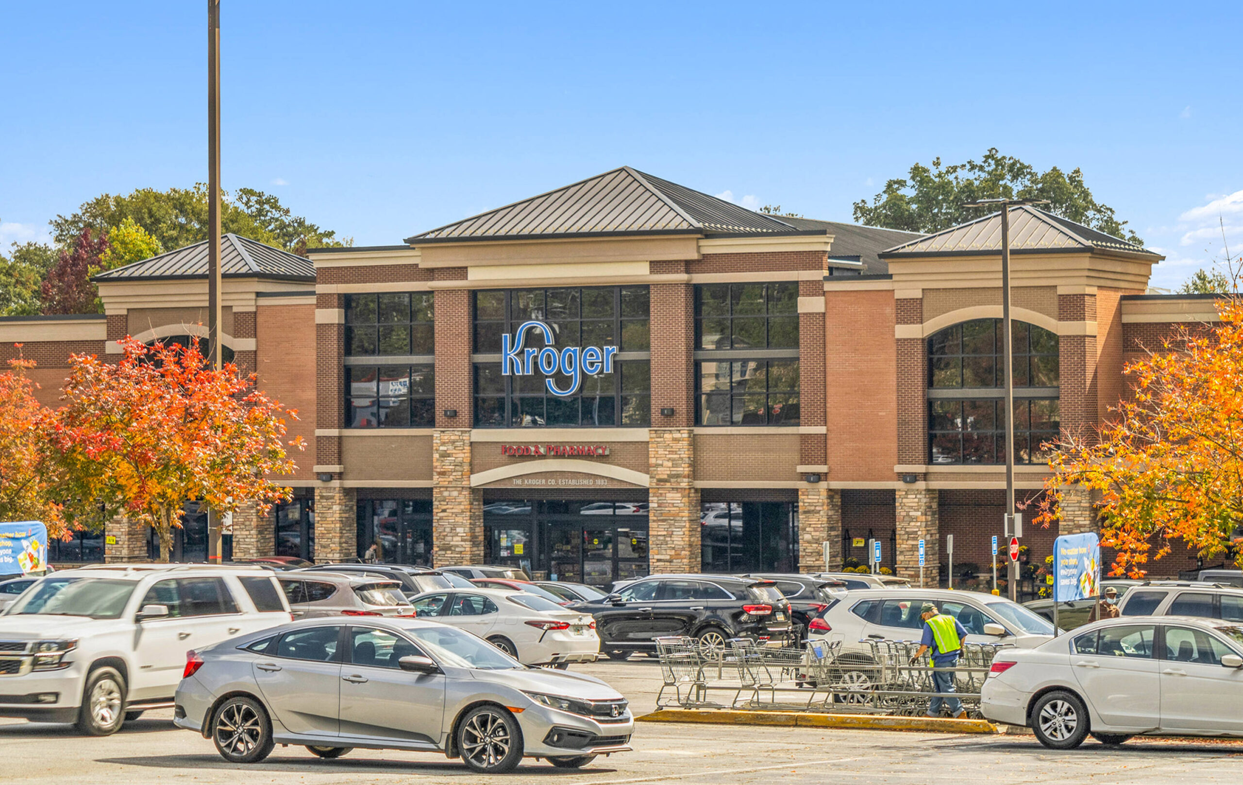 Front exterior of a Kroger grocery store with storefront signage visible, main entrance doors, and a parking lot in front.