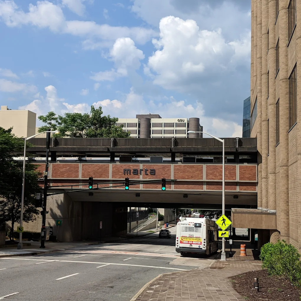 An exterior view of the Georgia State MARTA station bridge over a city street with a MARTA bus parked below.