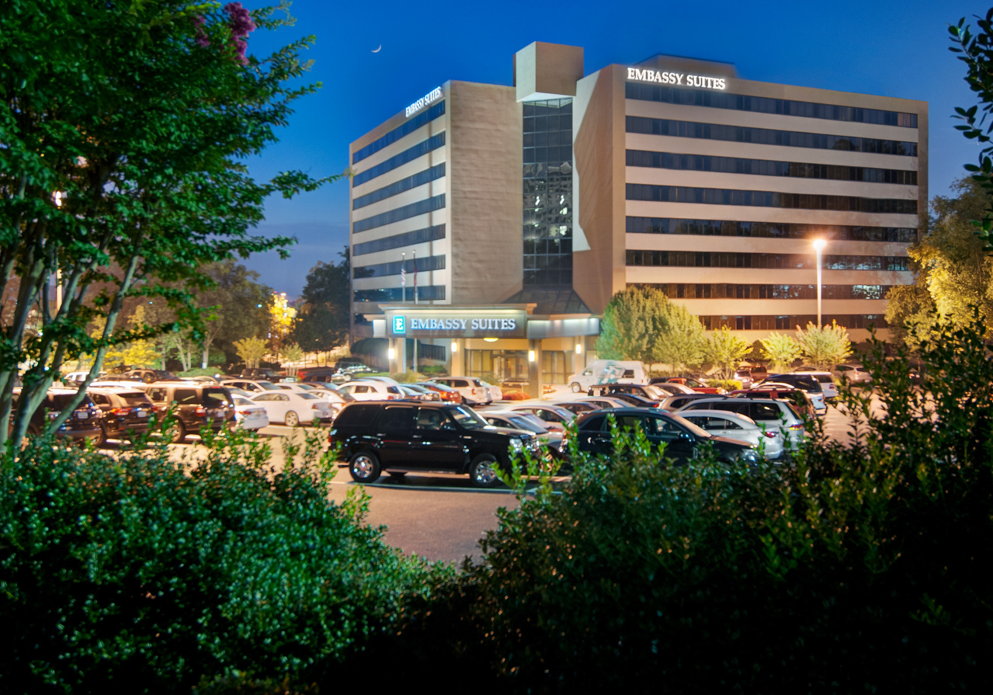 Exterior wide-angle view of the multi-story brick and glass facade of the Embassy Suites hotel on Akers Mill Road in the Cumberland Galleria area of Cobb County, Georgia.