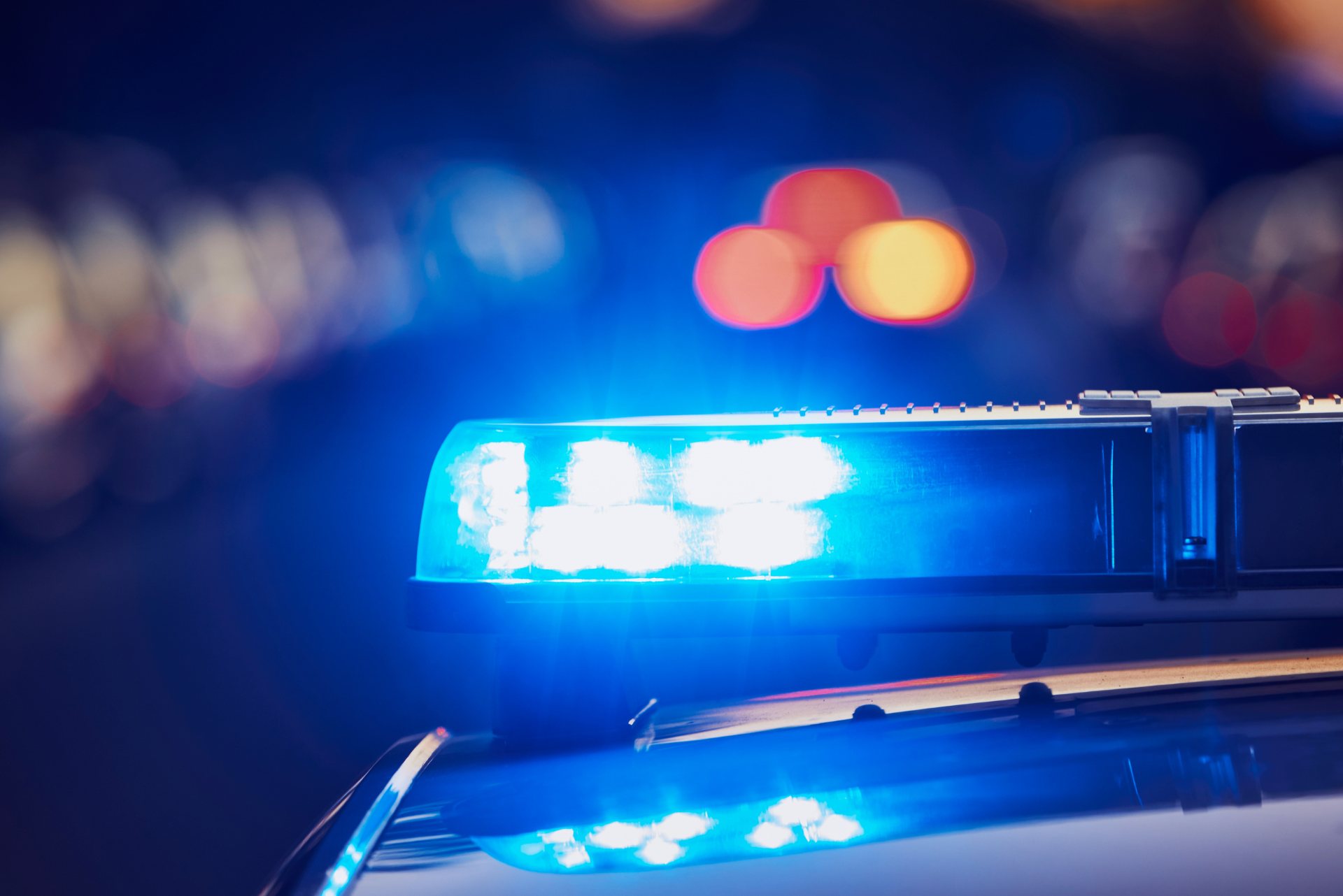 Close-up of glowing blue emergency lights on top of a police car at night.