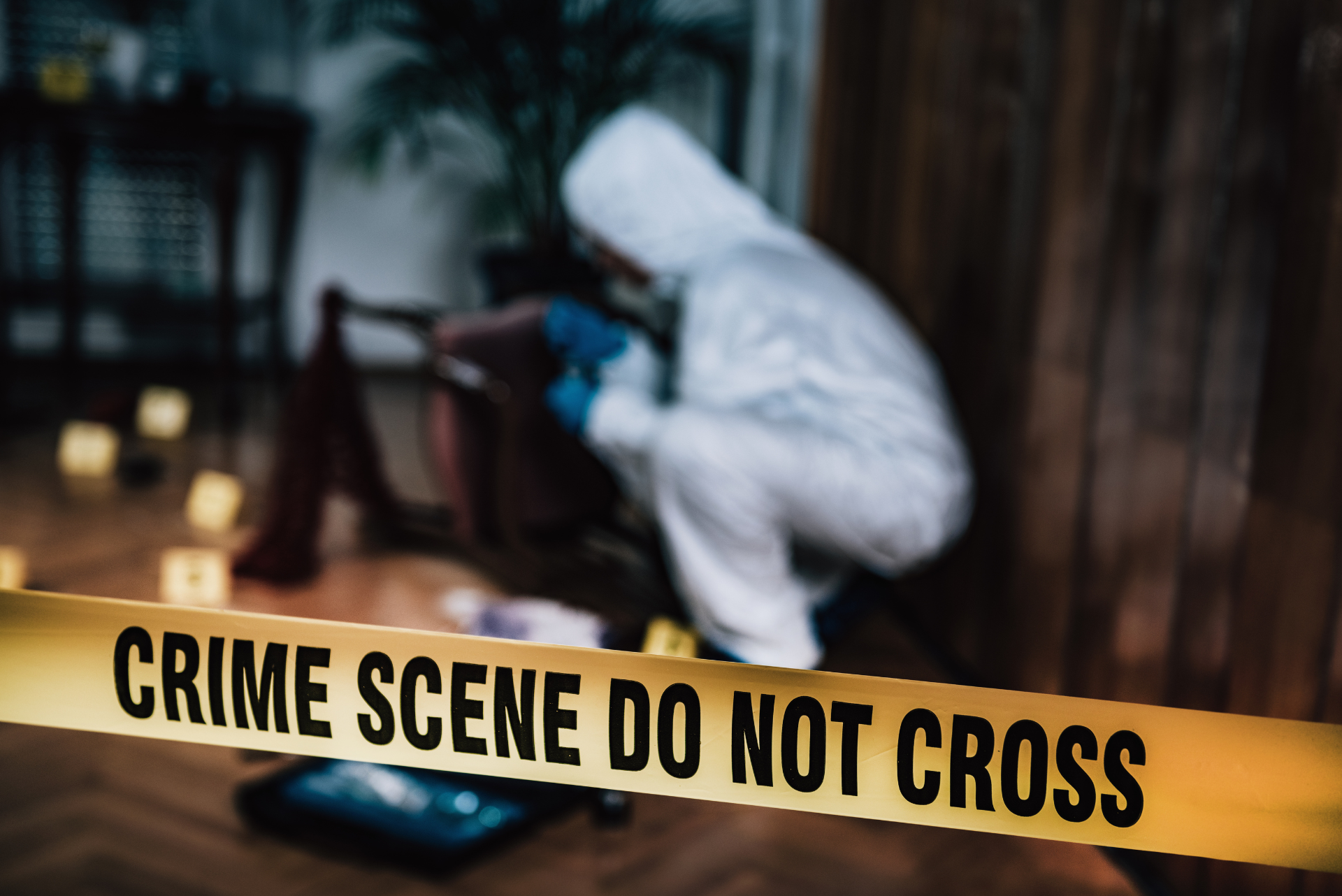 Jarvis Elliott and Travis Williams Fatally Shot in 601 Club Bar Shooting in Dunn, North Carolina: What Are the Legal Options for Victims and Families? Yellow "CRIME SCENE DO NOT CROSS" police tape in the foreground, with a crime scene investigator in a white protective suit and blue gloves examining evidence markers in the background.