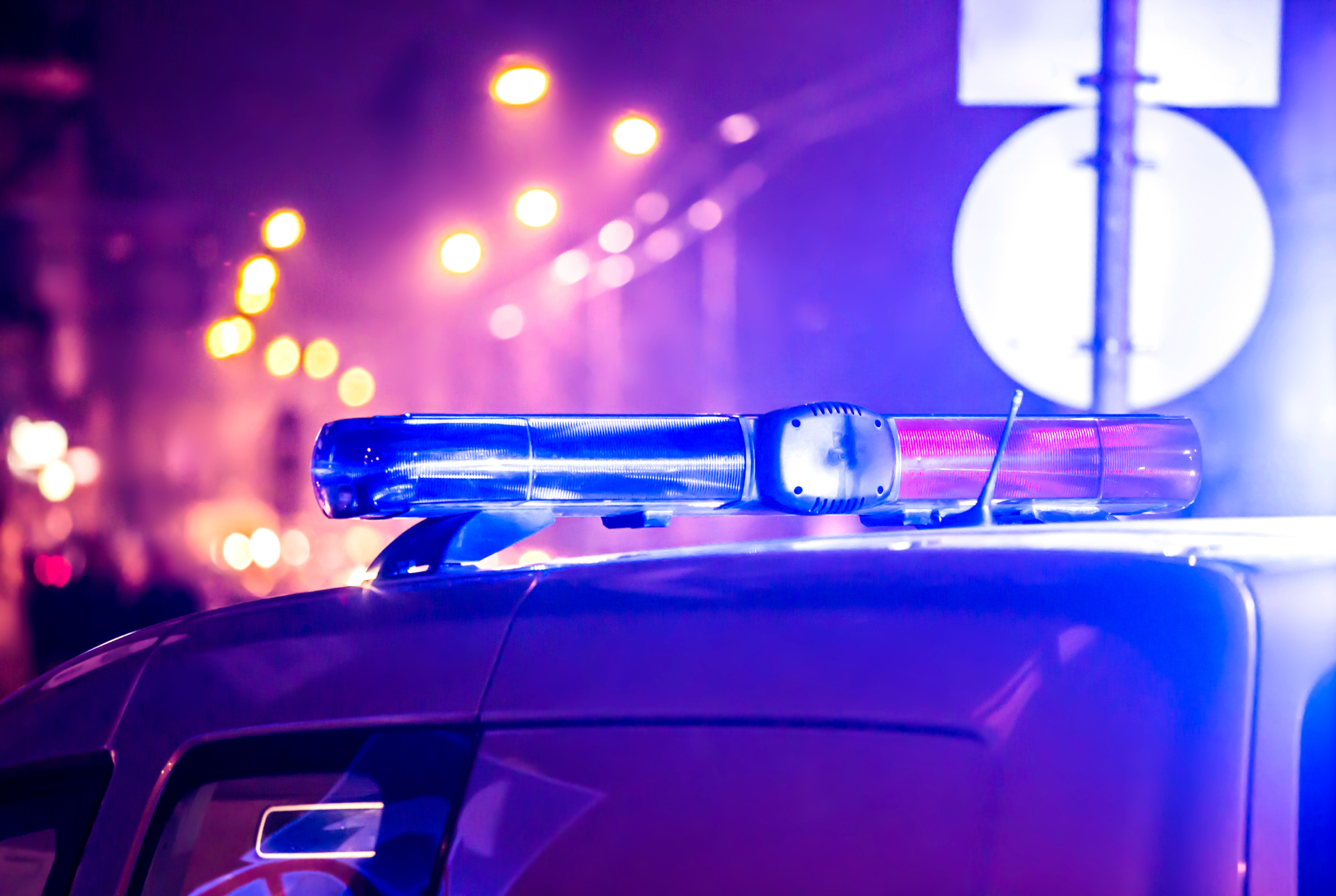 Blue and red emergency police vehicle lights flashing at night during an active law enforcement response scene.