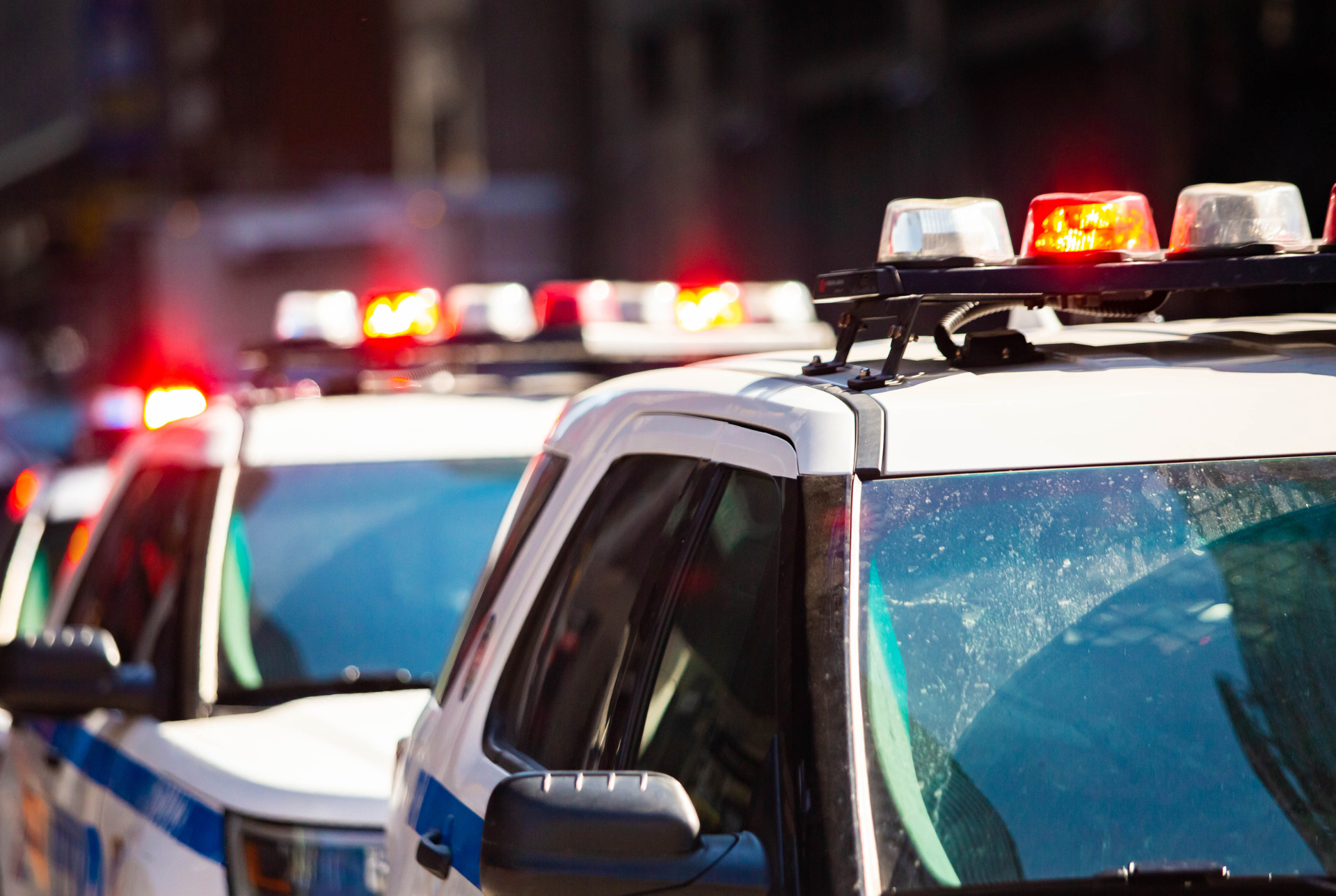 Police car headlights at dusk representing the deadly shootings at Hidden Pines Apartments in Atlanta.